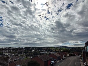 Ein Wohngebiet mit Häusern, einer Straße und einer hügeligen Landschaft im Hintergrund.