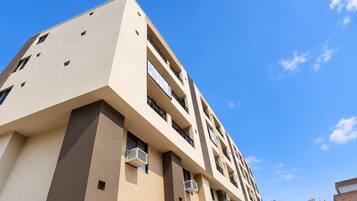 A multi-story building with balconies and air conditioning units.