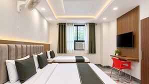 A hotel room with two beds, a desk, a TV, and a window with curtains. - Hotel AC Inn, Lucknow (Lucknow)
