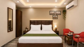 Una habitación de hotel con una cama grande, mesitas de noche, un escritorio con sillas y un equipo de aire acondicionado.