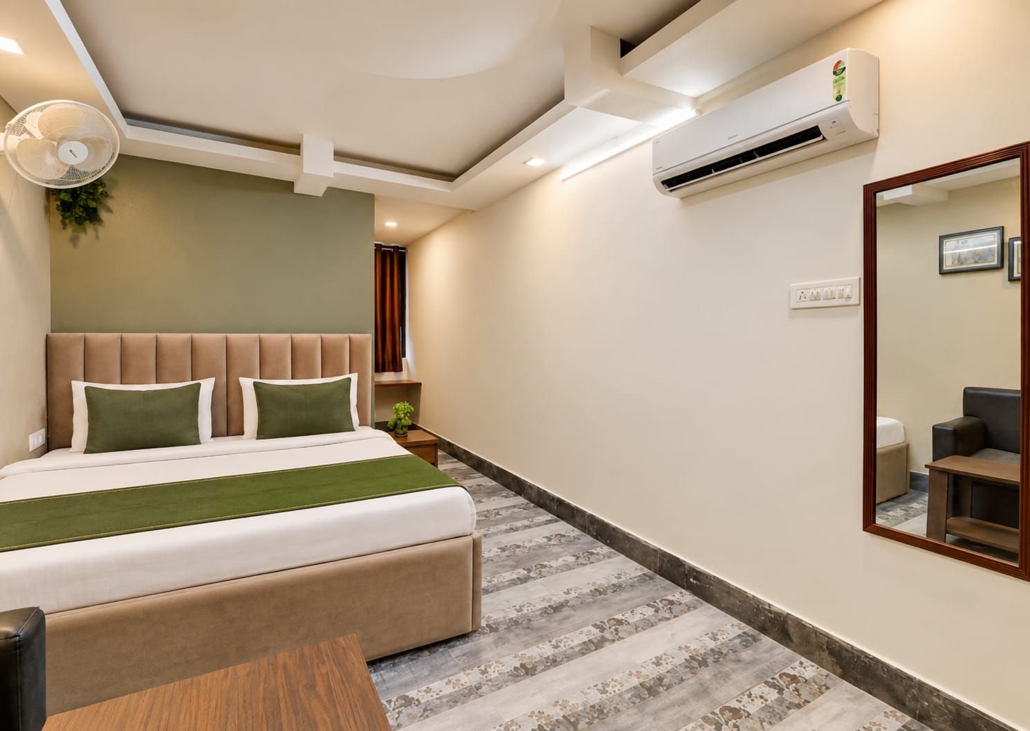 Una habitación de hotel con cama, mesita de noche, aire acondicionado y espejo.