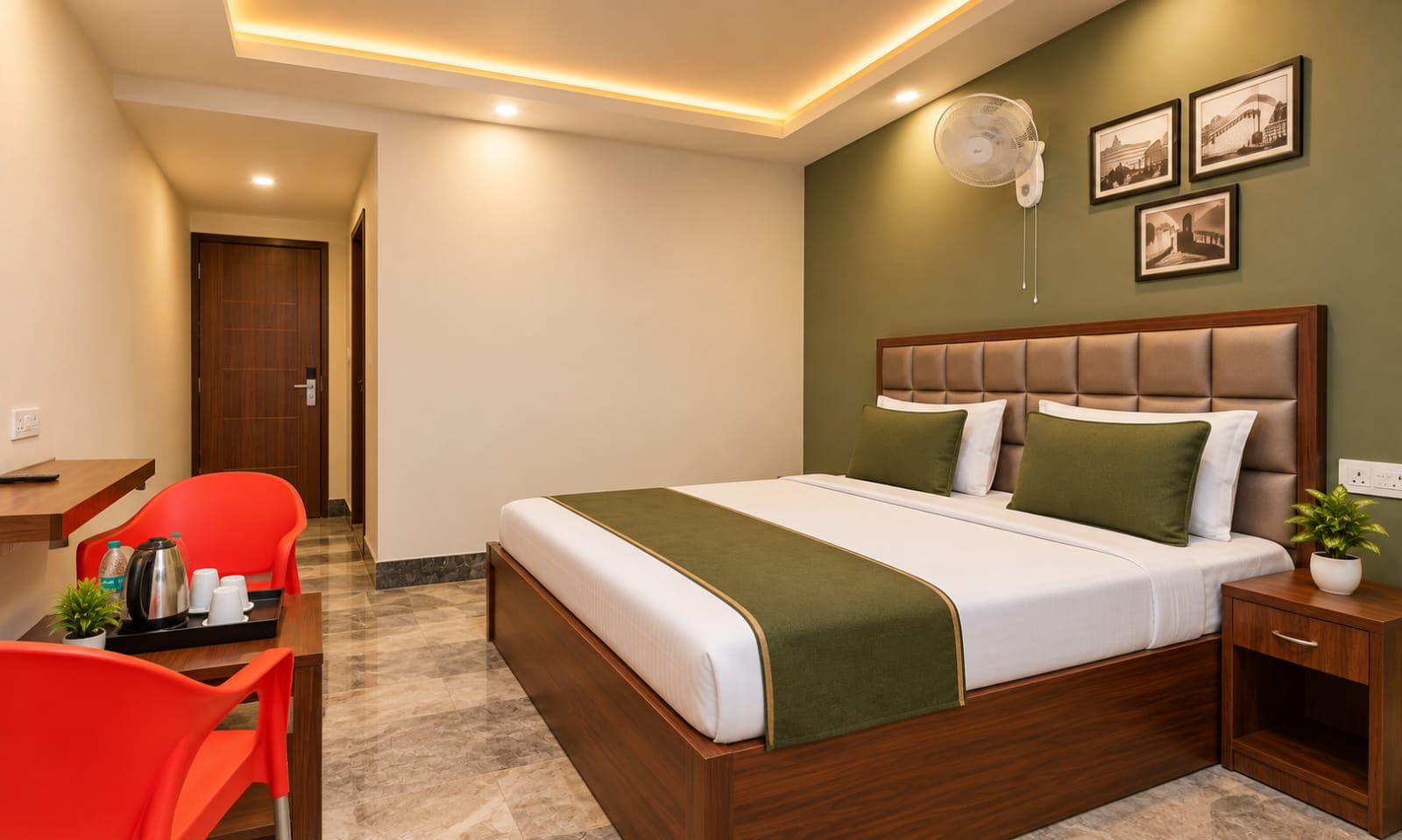 Una habitación de hotel con cama, escritorio, silla, mesita de noche y un ventilador de pared.
