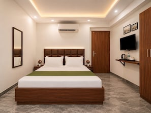 Een moderne hotelkamer met een groot bed, een flatscreen televisie, een houten garderobe en een klein nachtkastje.