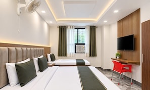 Habitación de hotel con dos camas, un escritorio, un televisor y una ventana con cortinas.
