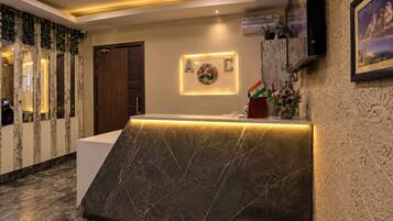 A reception area with a marble counter, a wall-mounted A/C unit, and a framed picture.