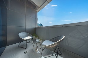 A balcony with two wicker chairs, a small table, and a potted plant. - StayShort - JVC Apartments Sleeps 2 in a Great Location! (JVC)