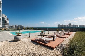 A rooftop pool area with lounge chairs and a swimming pool, surrounded by a cityscape. - StayShort - JVC Apartments Sleeps 2 in a Great Location! (JVC)