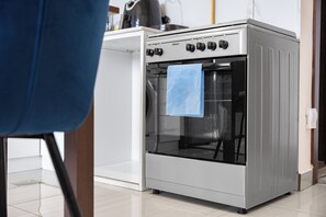 A kitchen with a stainless steel oven, a blue towel hanging on the oven door, and a white countertop. - StayShort - JVC Apartments Sleeps 2 in a Great Location! (JVC)
