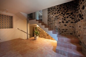 A staircase with a stone wall and a patterned wall on the left.