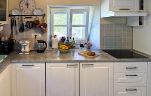 A kitchen with white cabinets, a coffee maker, a window with a view of greenery, and various kitchen utensils. - Gorgeous home in Risika with private swimming pool, can be inside or outside (Risika)