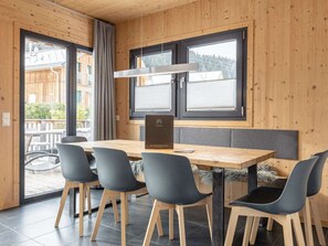 A wooden interior with a dining table, four chairs, and a menu stand. - One-bedroom Cabin (Sankt Georgen am Kreischberg)