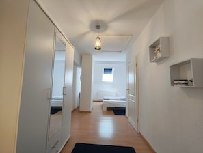 En gang der fører til et soveværelse med en seng, en radiator og et vindue.
