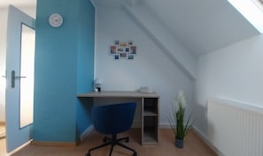 Habitació amb escriptori, cadira i rellotge de paret.