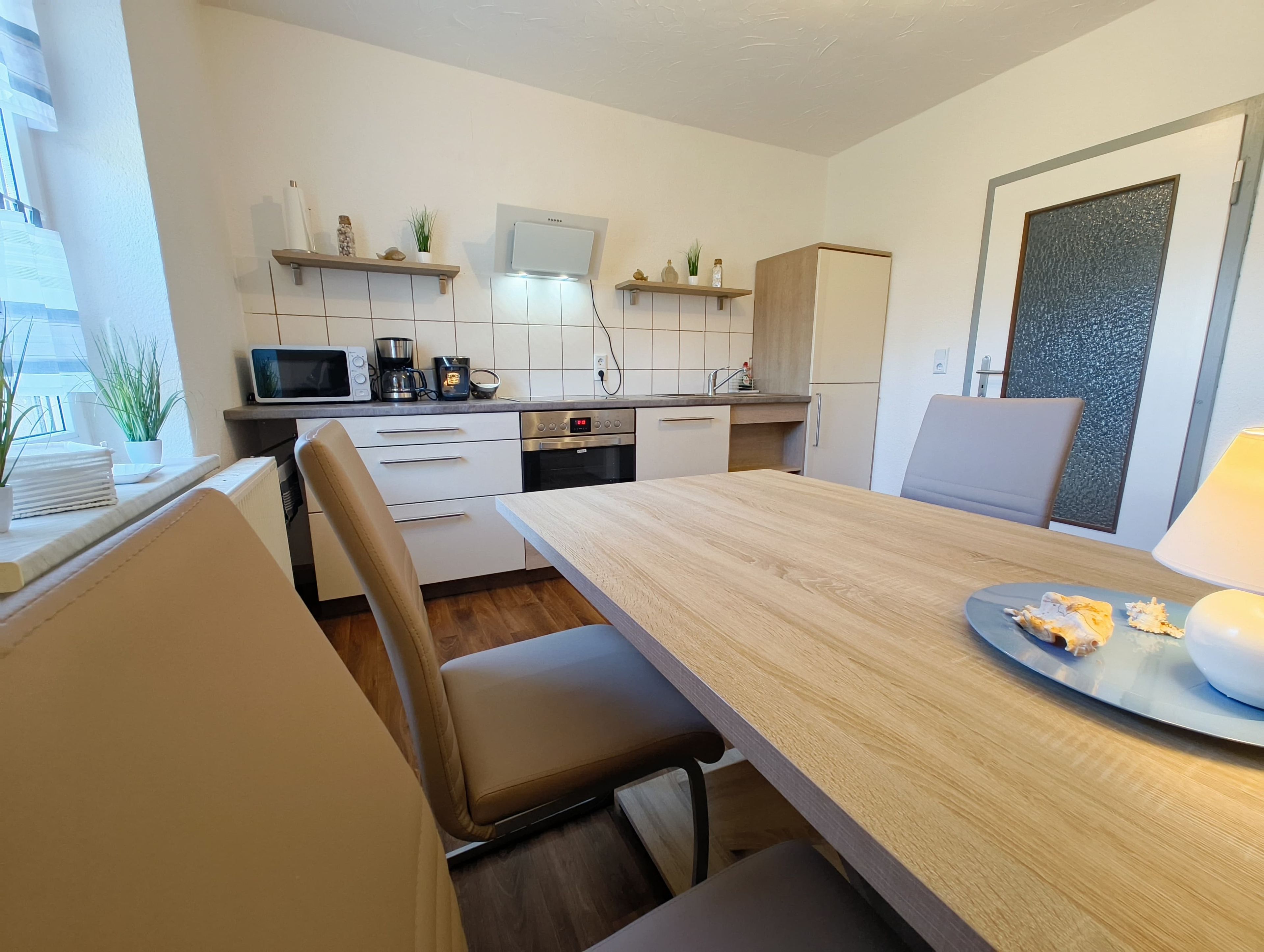 Eine moderne Küche mit weißen Schränken, einem Holzespeisetisch und einem eingebauten Backofen.