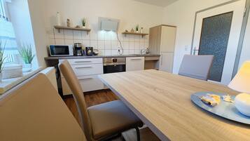 Eine moderne Küche mit weißen Schränken, einem Holzespeisetisch und einem eingebauten Backofen.