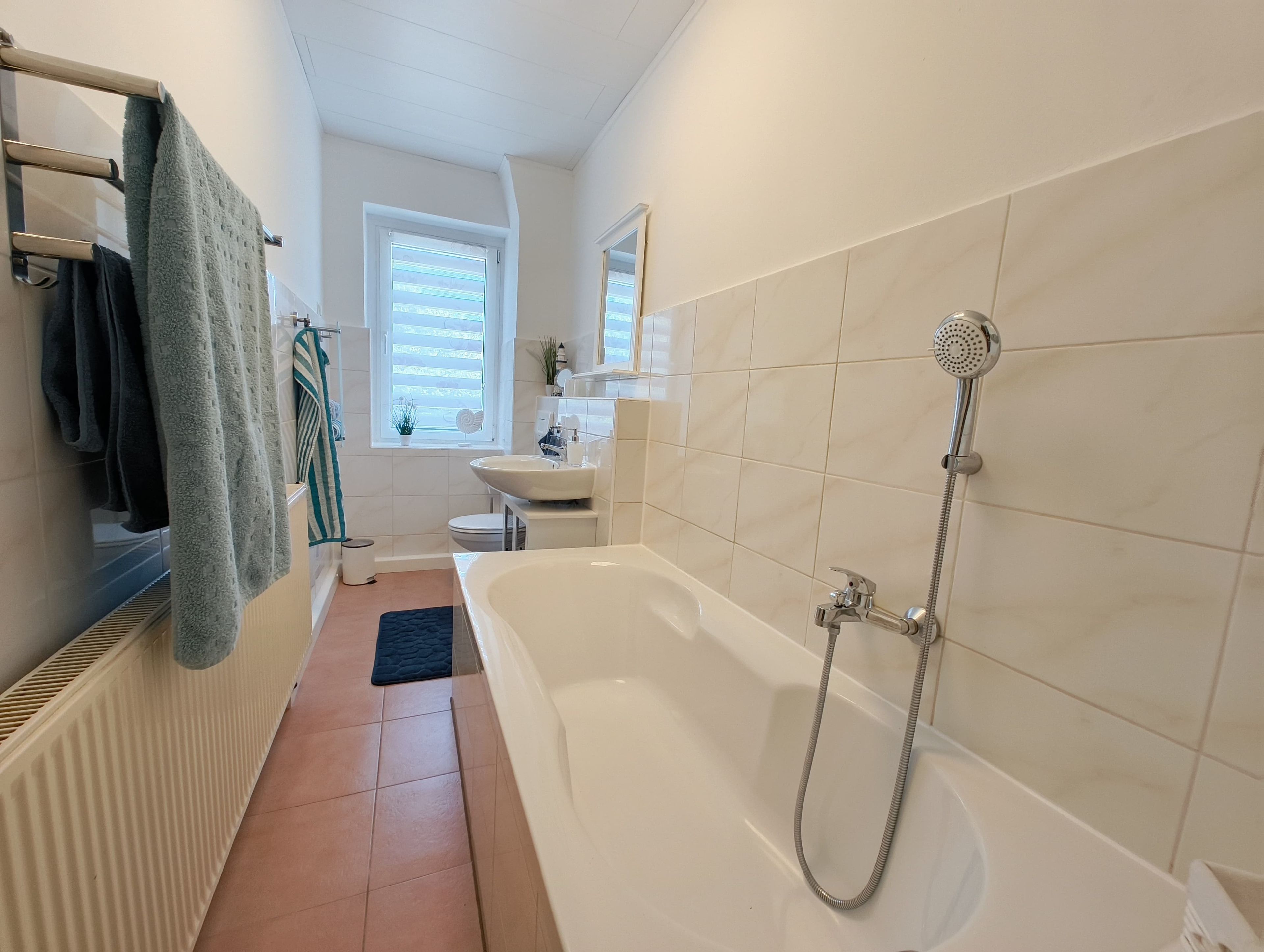 Et badeværelse med badekar, toilet og vask.