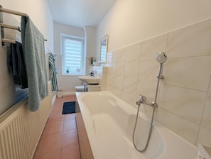 Et badeværelse med badekar, toilet og vask.