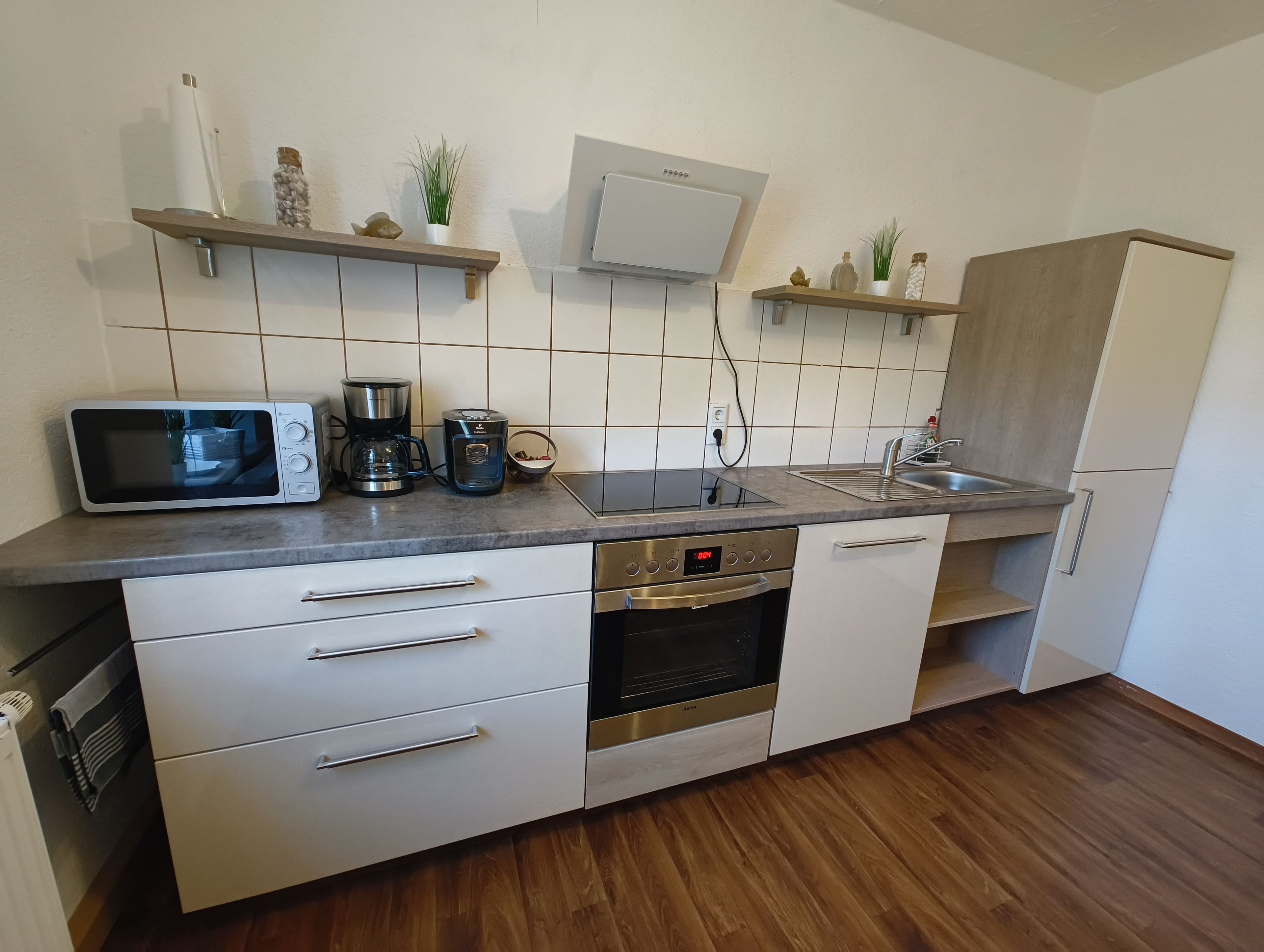 Cozinha moderna equipada com micro-ondas, cafeteira, forno e máquina de lavar louça embutida.