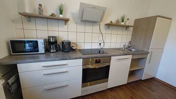 Cozinha moderna equipada com micro-ondas, cafeteira, forno e máquina de lavar louça embutida.