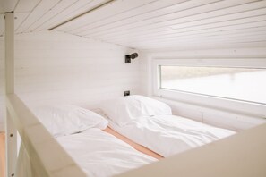 Een eenpersoonsbed in een kamer met witte muren en een raam.