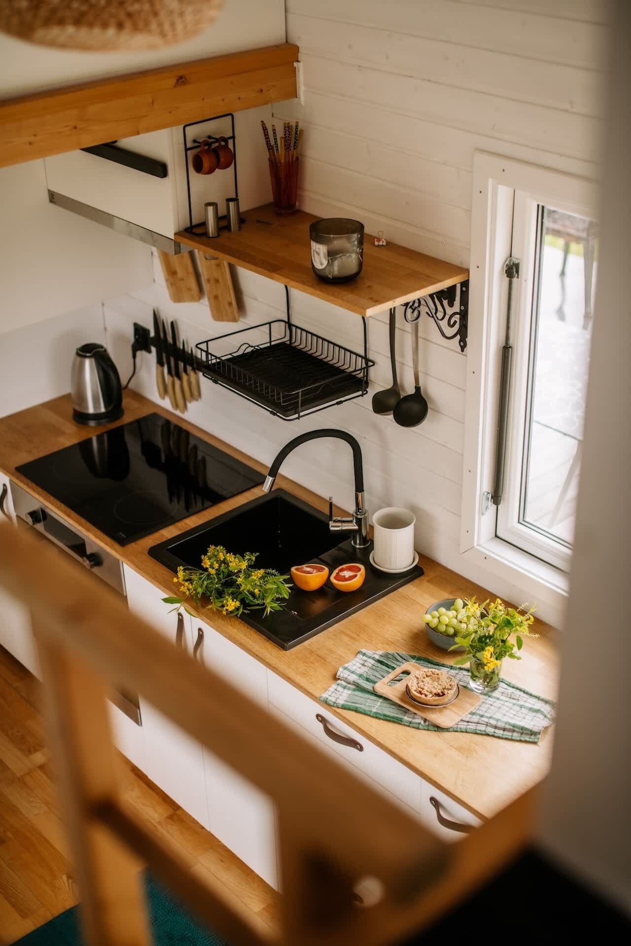 A kitchen with a black stove, a sink, and a window.
