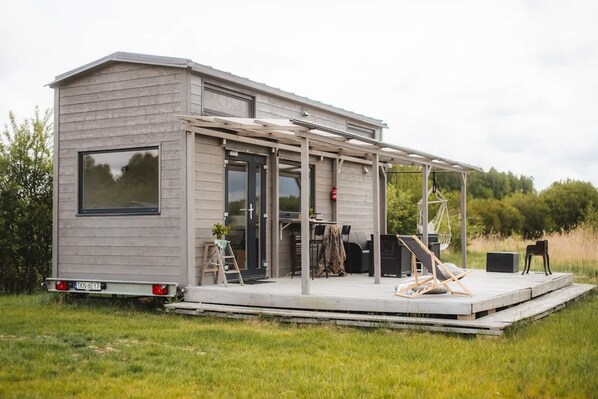 Een klein, gelijkvloers huis met een overdekt terras.
