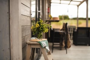 A wooden bench with a potted plant on a wooden stool outside a building.