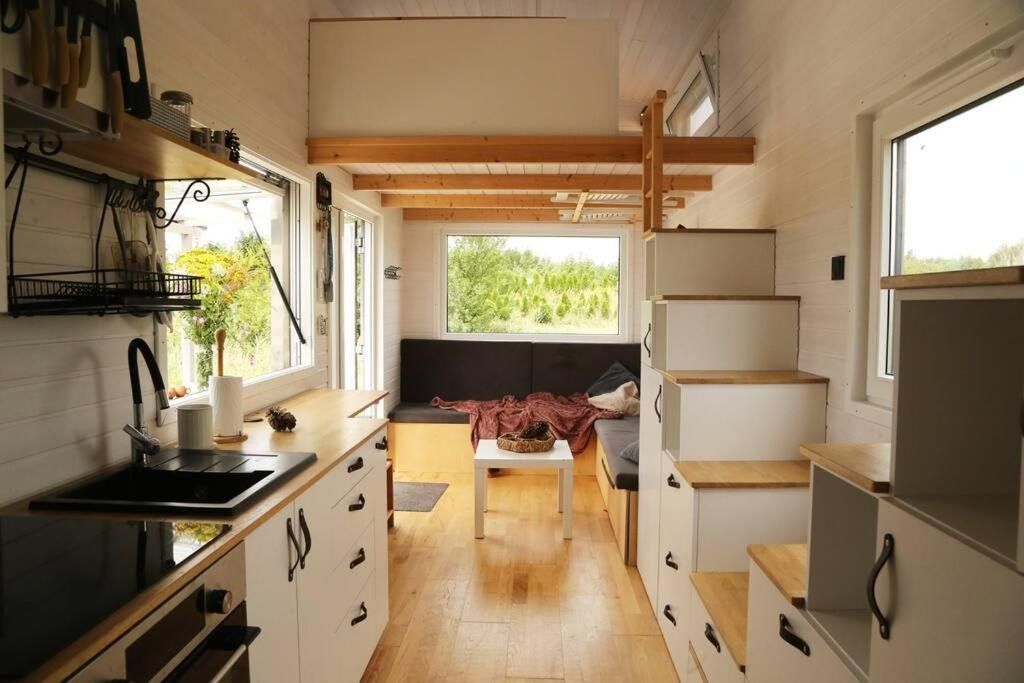 A compact kitchen with a sink, cabinets, and a window providing a view of greenery.