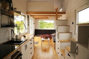 A compact kitchen with a sink, cabinets, and a window providing a view of greenery. - Cosy Tiny House by the Water, Close to Nature (Gabrielnia)