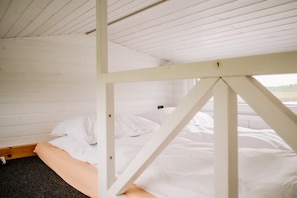 Una habitación con cama, paredes blancas y techo inclinado.