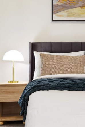 A neatly made bed with a dark headboard, a white pillow, a beige pillow, and a dark blue blanket. - Suite 1108 : Spacious CBD 3 Beds +Pool, Gym & Parking (Brisbane City)