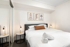 A hotel room with a bed, two bedside tables, and three wall-mounted artworks. - Central Eco-Luxe 2BR, 2BTH • Pool, Gym & Parking (Brisbane City)