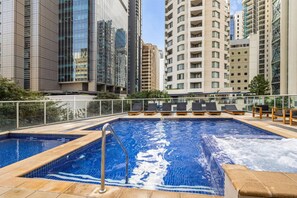 A rooftop pool with lounge chairs, surrounded by high-rise buildings. - Central Eco-Luxe 2BR, 2BTH • Pool, Gym & Parking (Brisbane City)