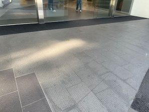 A tiled floor with a glass entrance and a person walking in the background. - Central Eco-Luxe 2BR, 2BTH • Pool, Gym & Parking (Brisbane City)