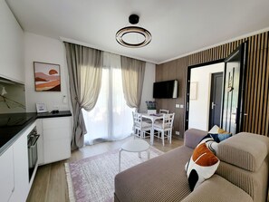 A modern living room with a sofa, a dining table, and a kitchen area. - Large, modern villa consisting of 4 fully equipped, independent apartments (Saint-Paul-de-Vence)