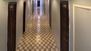 En hotelgang med skakternet gulv, døre på begge sider og et grønt oplyst loft.