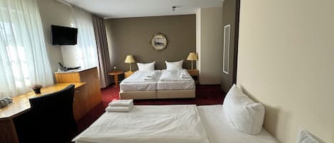 A hotel room with a bed, a desk, a television, and a wall-mounted picture.