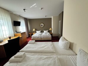 A hotel room with a bed, a desk, a television, and a wall-mounted picture. - Bonverde Hotel (Berlin)