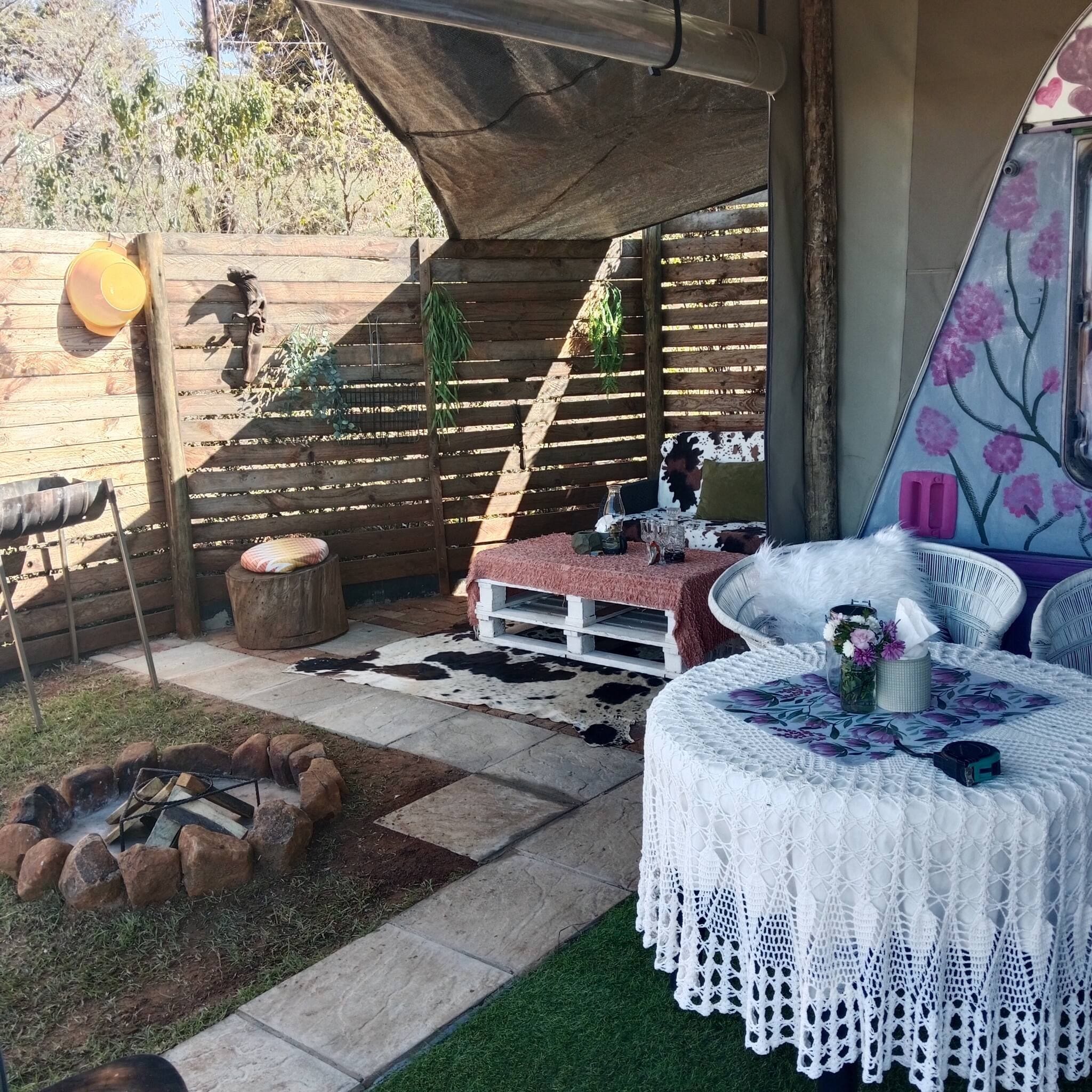 A cozy outdoor seating area with a fire pit, a wooden table, and a covered bench.