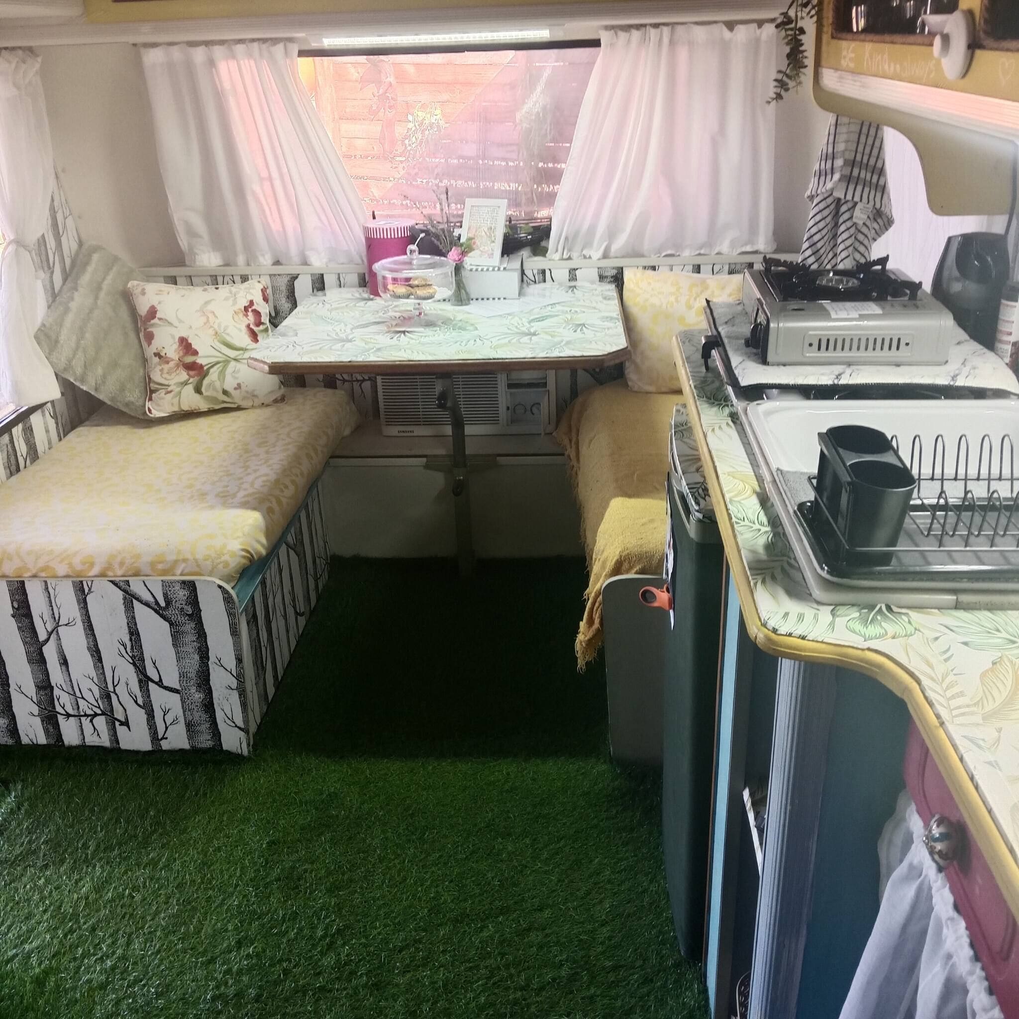Un espacio habitable compacto con kitchenette, una mesa de comedor y una pequeña zona de estar.