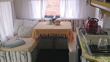 Una kitchenette compacta con un lavamanos, hervidor y una mesa pequeña con un cuenco de fruta.