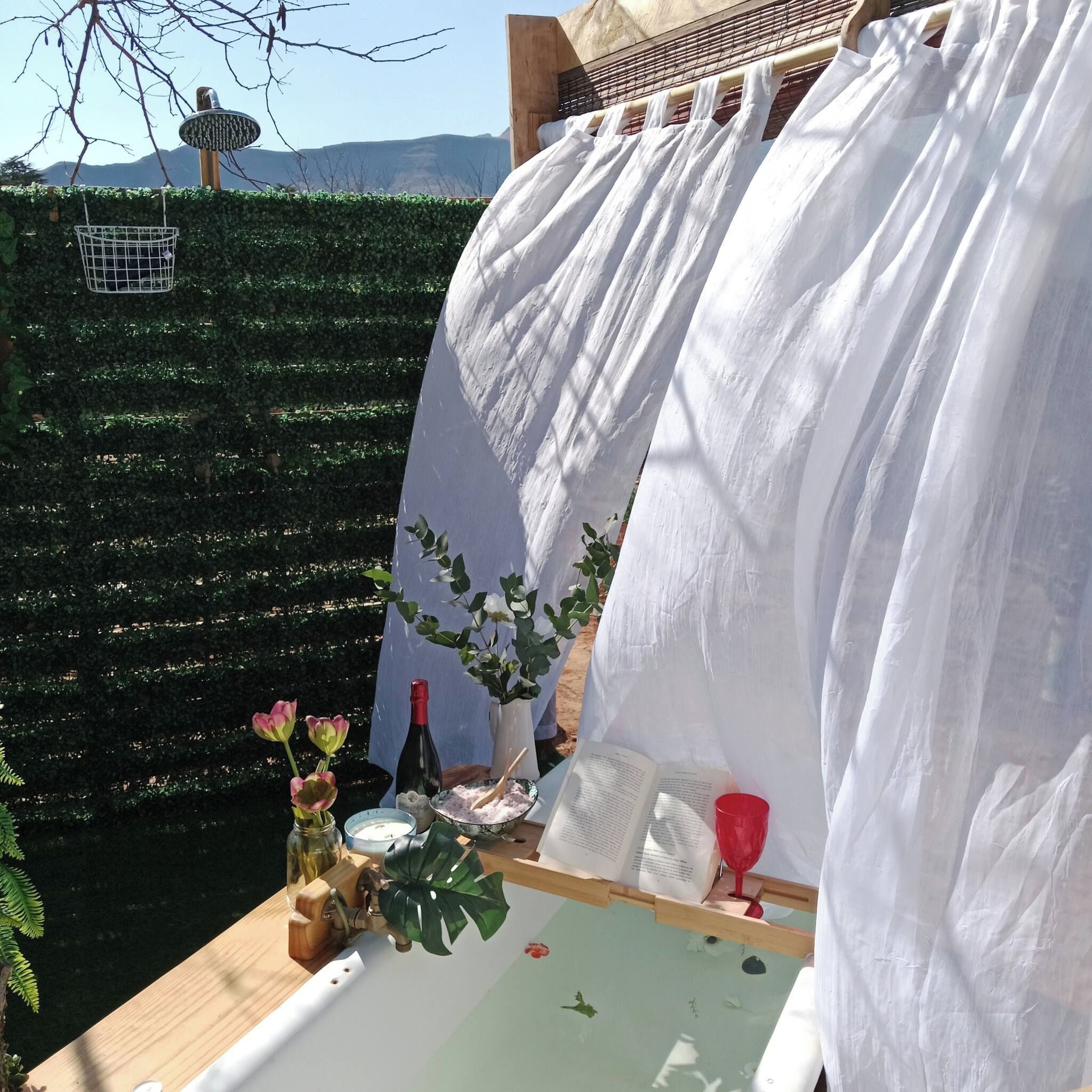 Una mesa dispuesta con un libro, una botella de vino, un florero con flores y una copa.