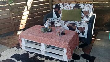 Un espacio al aire libre acogedor con alfombra de vaca, un banco blanco y un sofá estampado.