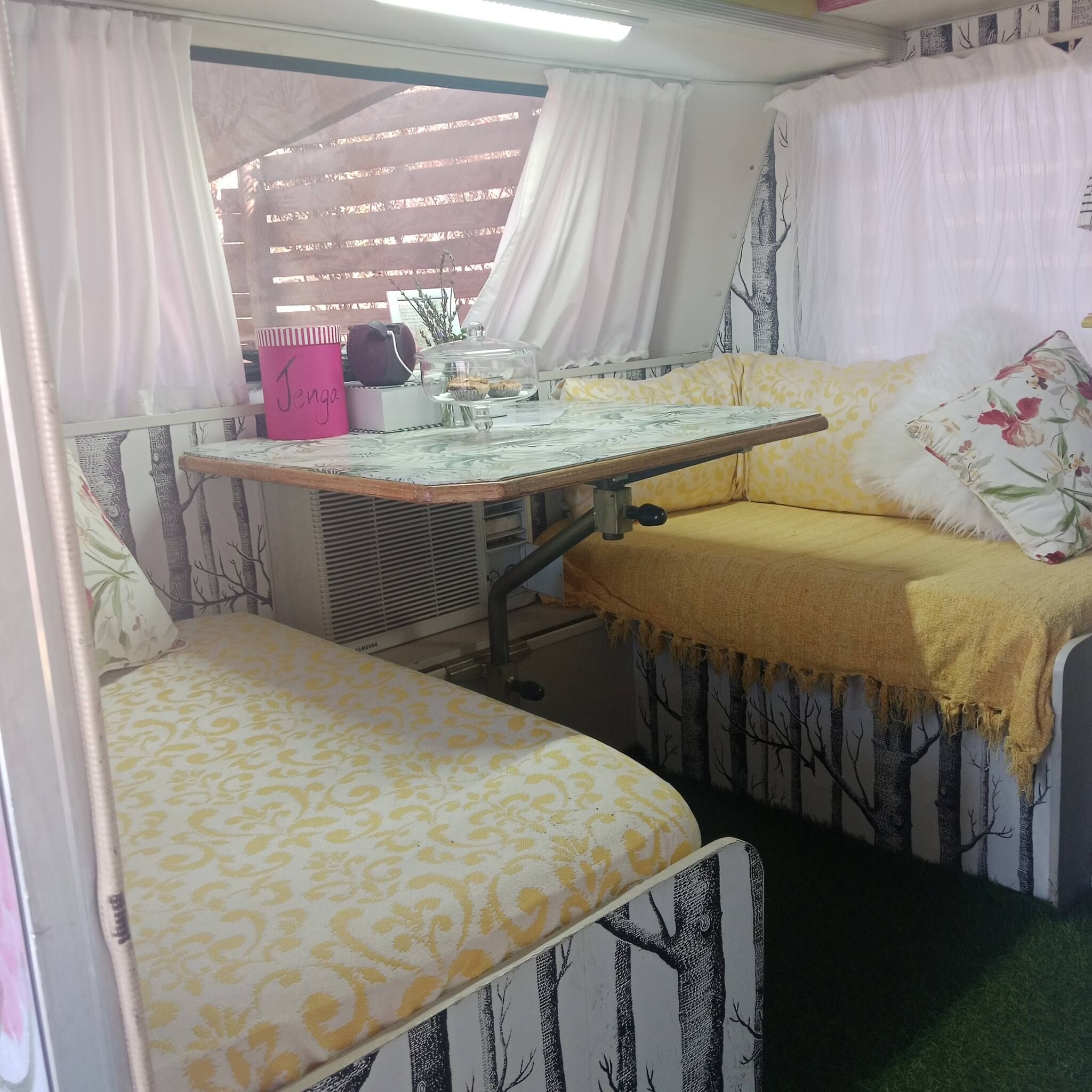 Un espace de vie compact comprenant un lit, une petite table avec un plateau en verre et une chaise.