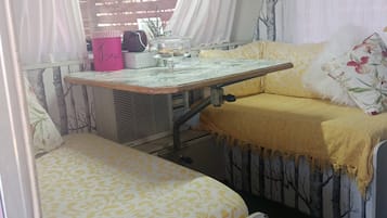 Un espace de vie compact comprenant un lit, une petite table avec un plateau en verre et une chaise.