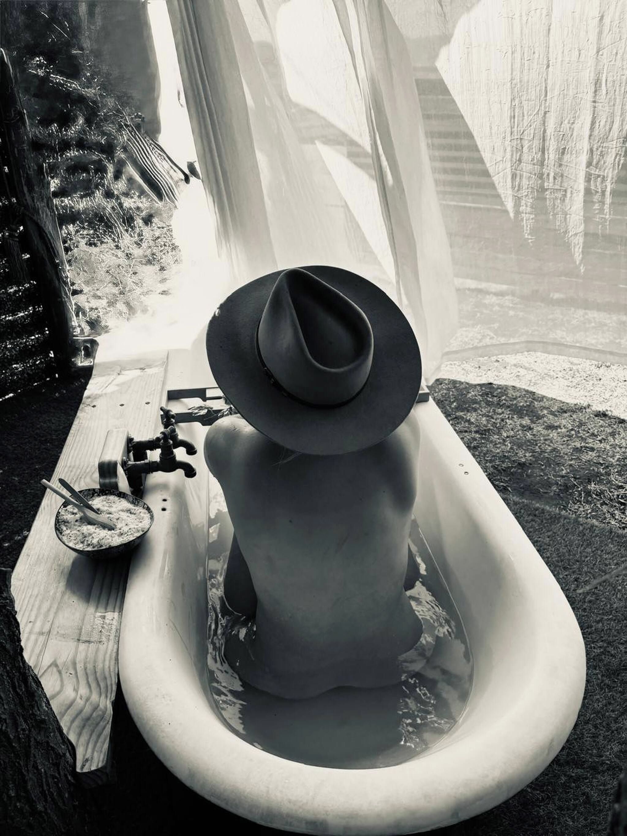 Una bañera con un sombrero encima, un cuenco con una cuchara y un grifo.