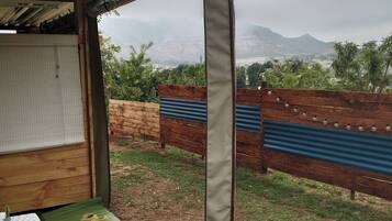 A covered outdoor seating area with a view of a mountainous landscape.