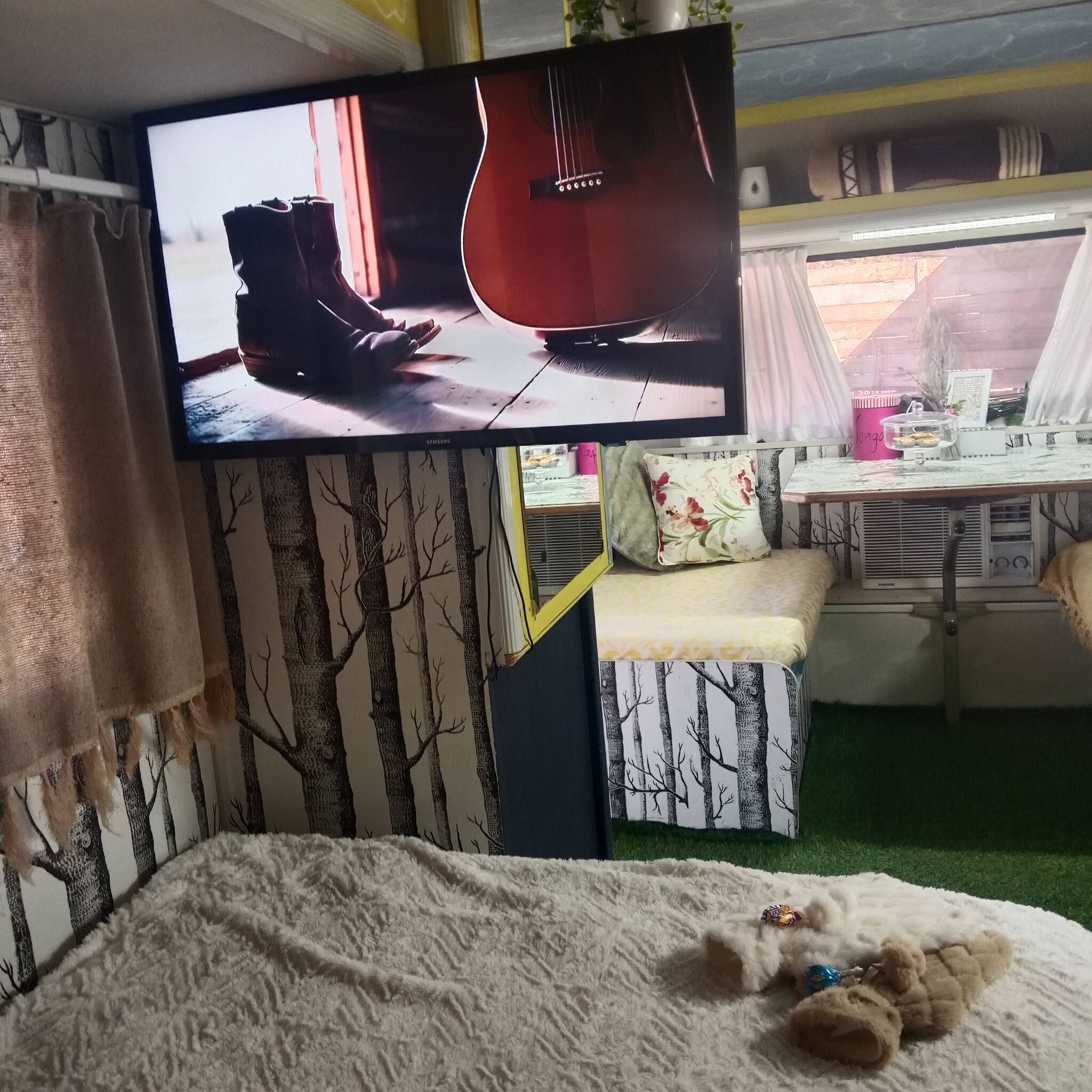 Une chambre à coucher avec un lit, un téléviseur fixé au mur, un bureau et une chaise.