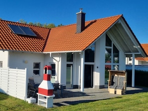 A modern house with a red-tiled roof, a chimney, and a covered outdoor area with a table and chairs. - "captain Dornfelder" (Trent)