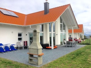 A building with a tiled roof, a covered patio area with seating, and a chimney. - "captain Dornfelder" (Trent)